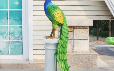 花園里一只立在石柱上的玻璃鋼彩繪孔雀雕塑
